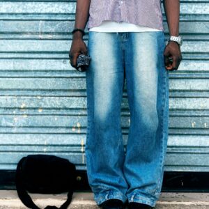 Street style featuring casual denim jeans, striped shirt, and accessories against a metal backdrop.